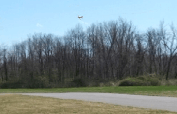 Is this plane turning in front of or behind the trees?