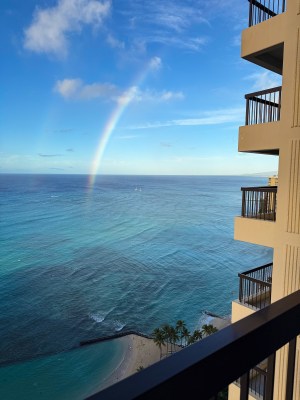 Double rainbows seen at sunrise against an ocean already busy with surfers catching waves at Canoes break - a day at Kuhio Beach Park